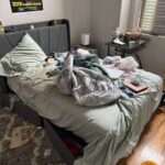 Cluttered bedroom before professional organizing service — unmade bed, clothes and items scattered.