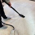 Professional cleaning service – vacuuming a white carpet, only legs visible