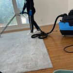 Professional carpet cleaning with vacuum equipment in Los Angeles home